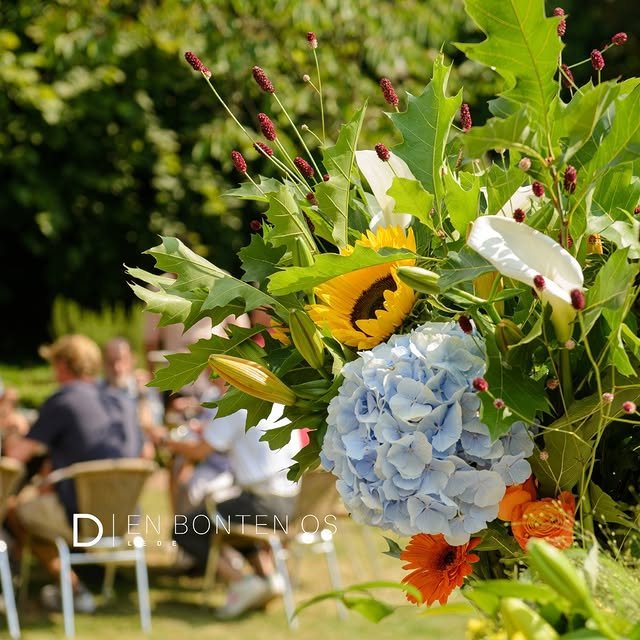 Bloemen in de tuin van Den Bonten Os met gasten op het terras